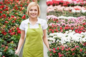 fiori esperto. superiore Visualizza di bellissimo biondo capelli donna in piedi nel fiore letto e sorridente foto