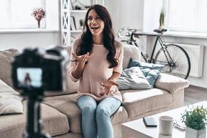 moderno influencer. femmina vlogger fabbricazione sociale media video mentre seduta in casa foto