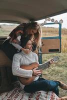 giocando musica lei piace. bello giovane uomo giocando chitarra per il suo bellissimo fidanzata mentre seduta nel retrò stile mini furgone foto