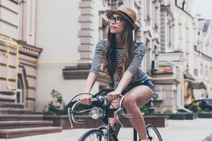 l'esame nuovo posti. bellissimo giovane donna equitazione bicicletta lungo il strada e guardare curioso foto