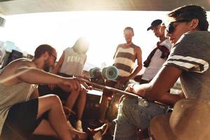 caldo sole e migliore gli amici. gruppo di pattinatore amici sospeso su insieme mentre riposo sotto il ponte all'aperto foto