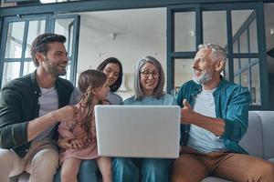 contento famiglia utilizzando il computer portatile e sorridente mentre la spesa tempo casa insieme foto