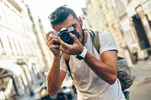 giovane uomo nel casuale capi di abbigliamento Fotografare con digitale telecamera mentre in piedi all'aperto foto