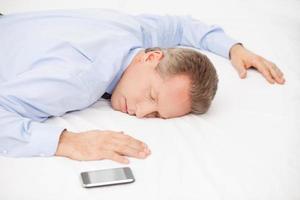 stanco uomo d'affari. superiore Visualizza di stanco grigio capelli uomo nel blu camicia addormentato su letto foto