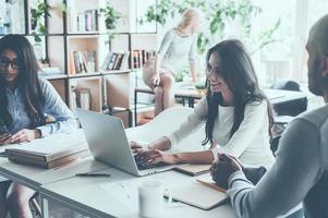 Lavorando momenti. gruppo di giovane attività commerciale persone Lavorando e comunicare insieme mentre seduta a loro Lavorando posti nel ufficio foto