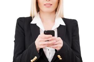 donna d'affari digitando un' Messaggio. ritagliata Immagine di maturo donna d'affari Tenere mobile Telefono mentre in piedi isolato su bianca foto