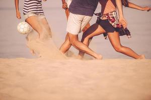 spiaggia palla nel movimento. ritagliata Immagine di giovane persone giocando con calcio palla su il spiaggia foto