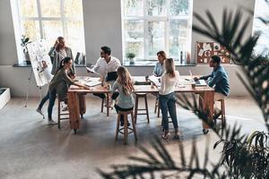 assunzione cura di attività commerciale. superiore Visualizza di Due moderno giovane colleghi conduzione un' attività commerciale presentazione mentre in piedi nel il tavola camera foto