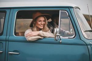 fare che cosa essi amore. attraente giovane sorridente donna guardare su il furgoni finestra mentre godendo il auto viaggio con sua fidanzato foto