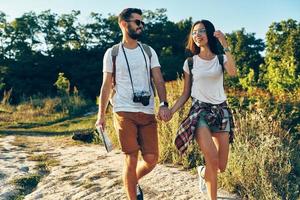 bellissimo giovane romantico coppia di turisti Tenere mani e sorridente mentre a piedi all'aperto foto