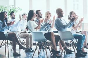 quello era veramente grande seminario. lato Visualizza di gruppo di giovane allegro persone seduta su conferenza insieme e Applaudire foto