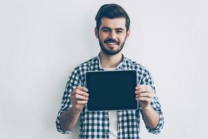 mostrando il suo marca nuovo tavoletta. bello giovane uomo mostrando il suo digitale tavoletta e sorridente foto