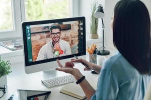 giovane donna parlando per collega di video chiamata mentre seduta nel ufficio foto