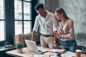 Due giovane collaboratori nel inteligente casuale indossare discutere attività commerciale mentre Lavorando nel ufficio insieme foto