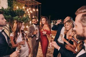 gruppo di bellissimo giovane persone nel vestito formale comunicare e sorridente mentre la spesa tempo su lusso festa foto