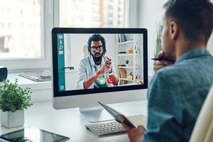 fiducioso giovane uomo parlando per collega di video chiamata mentre seduta nel ufficio foto