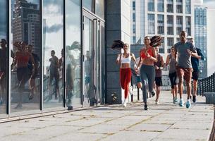 pieno lunghezza di persone nel gli sport capi di abbigliamento jogging mentre esercizio su il marciapiede all'aperto foto
