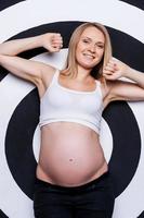 incinta donna. bellissimo incinta donna in posa mentre in piedi contro bersaglio sfondo foto