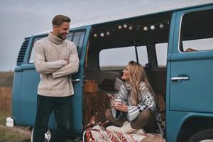 amore è nel il aria. bello giovane uomo guardare a il suo fidanzata e sorridente mentre godendo strada viaggio foto