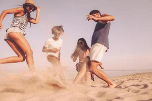 divertimento nel azione. gruppo di allegro giovane persone giocando con calcio palla su il spiaggia foto