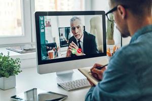 grave giovane uomo parlando per collega di video chiamata e fabbricazione Appunti foto