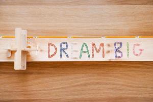 sognare grande. superiore Visualizza di sognare grande testo fatto a partire dal colorato graffette e di legno aereo posa su il legna grano foto