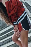 Perfetto stile. avvicinamento di giovane donna nel sport capi di abbigliamento pendente su il ringhiera mentre in posa su il le scale all'aperto foto