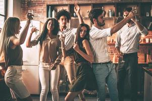 festa tempo allegro giovane persone danza e potabile mentre godendo casa festa su il cucina foto