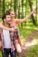 esplorando parco lato. contento giovane amorevole coppia a piedi nel parco mentre donna abbracciare uomo e puntamento lontano con Sorridi foto