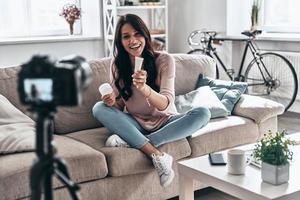 dando consiglio. femmina vlogger fabbricazione sociale media video e sorridente mentre seduta in casa foto
