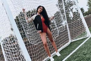 calcio ragazza. pieno lunghezza di attraente giovane donna nel sport capi di abbigliamento guardare a telecamera mentre in piedi vicino il obbiettivo inviare foto