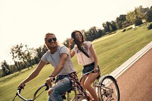 godendo grande fine settimana. bellissimo giovane sorridente coppia nel casuale indossare Ciclismo insieme mentre la spesa spensierato tempo all'aperto foto