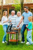 tempo per barbecue. pieno lunghezza di contento famiglia barbecue carne su griglia all'aperto foto