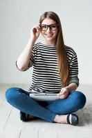 assunzione tempo per relax. bellissimo giovane donna nel a strisce capi di abbigliamento seduta su il pavimento e sorridente foto