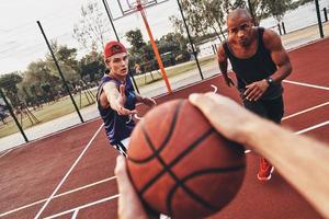 migliore gioco mai. vicino su di uomo Tenere palla mentre giocando pallacanestro con amici all'aperto foto