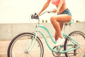 bellezza su bicicletta. avvicinamento di bellissimo giovane donna con Perfetto curve equitazione bicicletta foto