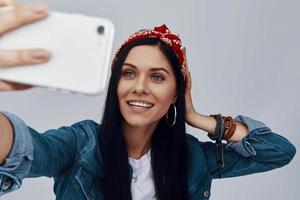 bellissimo giovane donna nel bandana fabbricazione autoscatto e sorridente foto