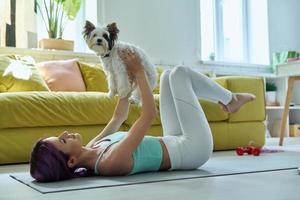 bellissimo giovane donna nel gli sport capi di abbigliamento esercizio con sua poco cane a casa foto
