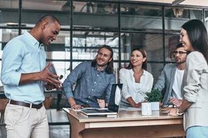 controllo il figure in linea. giovane moderno uomo mostrando digitale tavoletta per il suo colleghi mentre Lavorando nel il ufficio foto