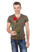bellissimo fiore per voi bello giovane uomo Tenere un' rosso rosa e sorridente mentre in piedi isolato su bianca sfondo foto