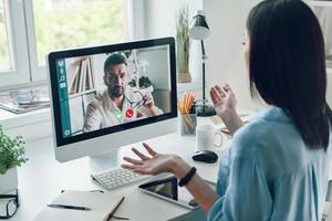 giovane donna parlando per collega di video chiamata mentre seduta nel ufficio foto