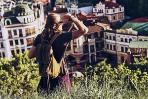 godendo il Visualizza. bello giovane uomo nel casuale capi di abbigliamento guardare a Visualizza mentre in piedi su il collina all'aperto foto