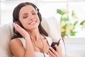 di partenza giorno con sua preferito musica. contento giovane donna nel cuffie ascoltando per mp3 giocatore e sorridente foto