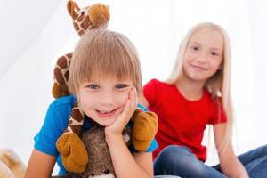 avendo divertimento insieme. Due carino bambini avendo divertimento mentre seduta insieme su letto foto