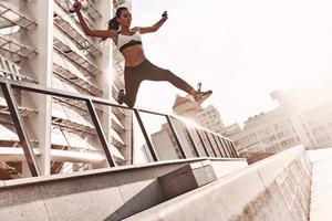 in direzione un' più sano stile di vita. pieno lunghezza di moderno giovane donna nel gli sport capi di abbigliamento salto mentre esercizio all'aperto foto