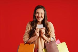 allegro giovane donna nel casuale capi di abbigliamento trasporto shopping borse e credito carta foto