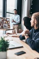 brainstorming. gruppo di giovane attività commerciale persone utilizzando lavagna con adesivo Appunti mentre Lavorando nel il ufficio foto