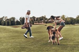 avendo così tanto divertimento. pieno lunghezza di bellissimo giovane coppia giocando con loro cane mentre la spesa tempo all'aperto foto