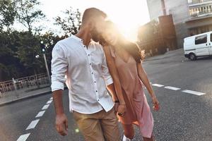lei è il suo universo. bellissimo giovane coppia Tenere mani e sorridente mentre a piedi attraverso il città strada foto