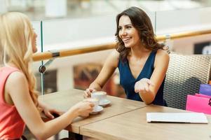 caffè rompere. Due bellissimo giovane donne assunzione un' rompere durante un' shopping viaggio foto